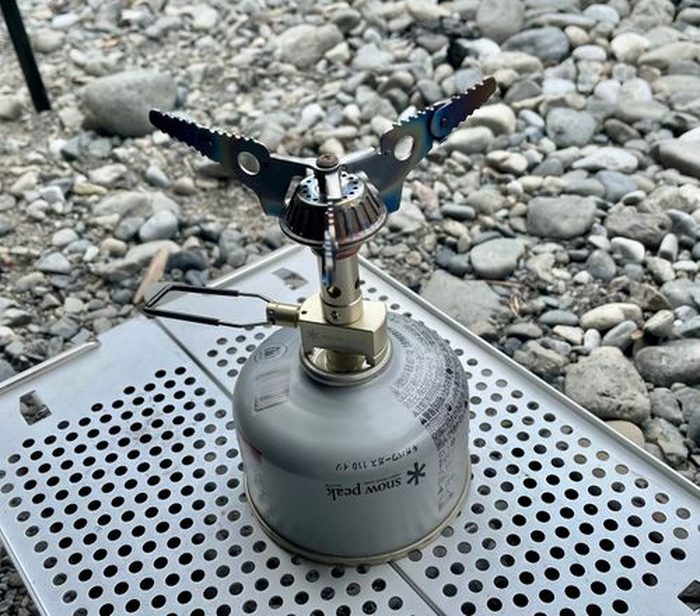 銀色のガス缶に装着したSOTOパワートーチ。焚き火場での着火準備